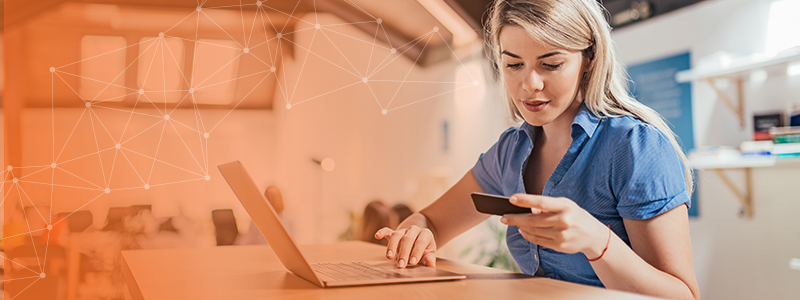 Woman sitting at her laptop while looking at her credit card